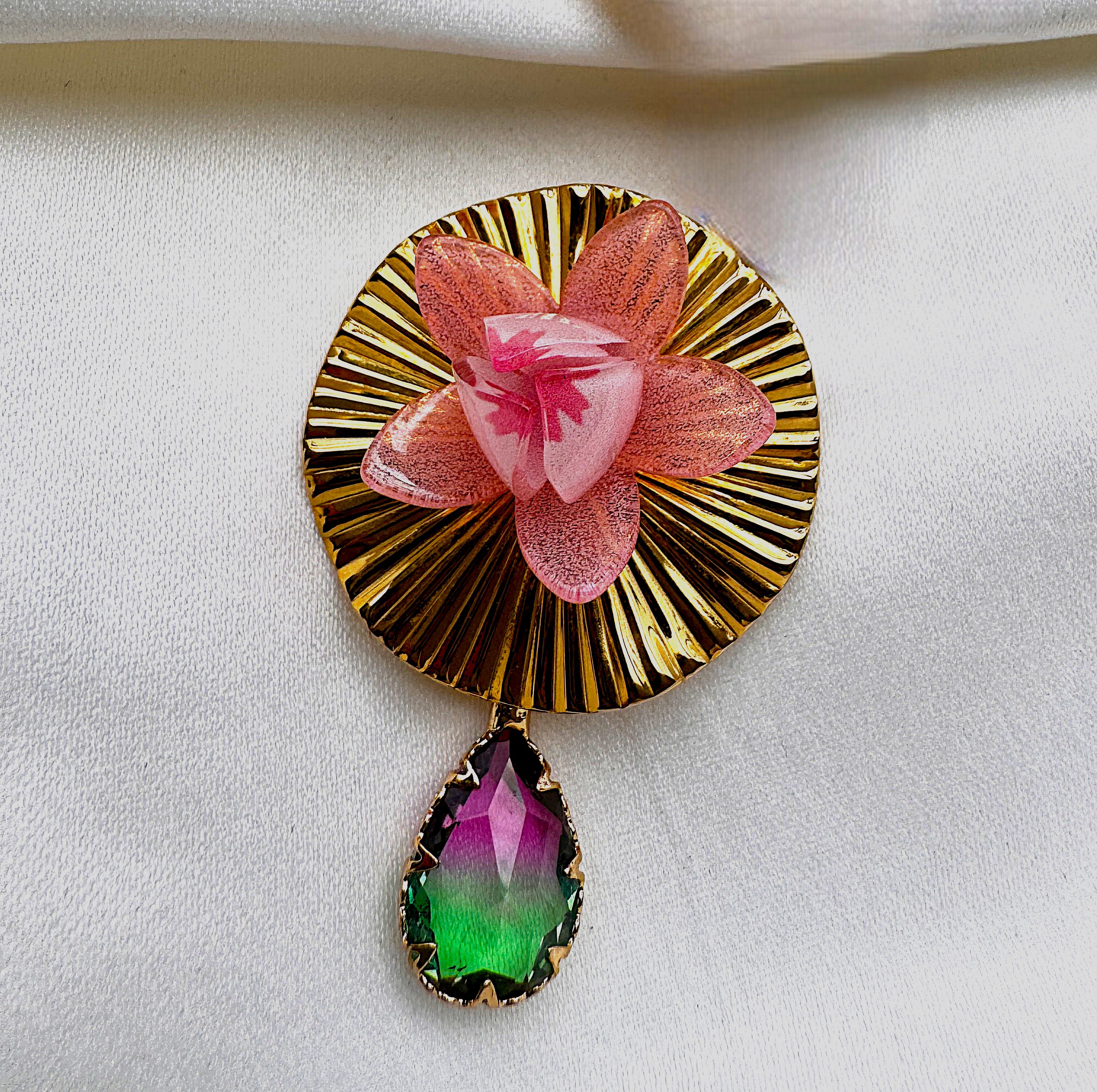 A Lotus Pod earring with a flower against a pleated gold fan and a crystal drop.