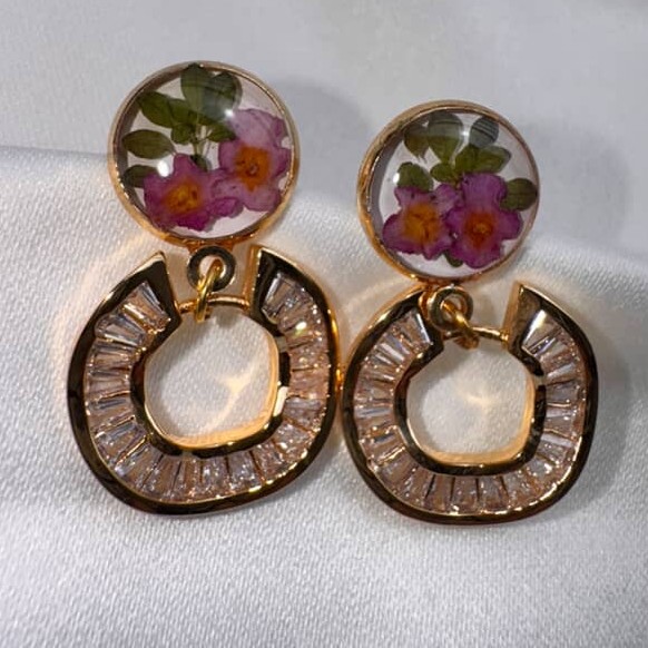 A pair of Blossom Gleam earrings with pressed violet flowers and a circular stud of baguette crystals.