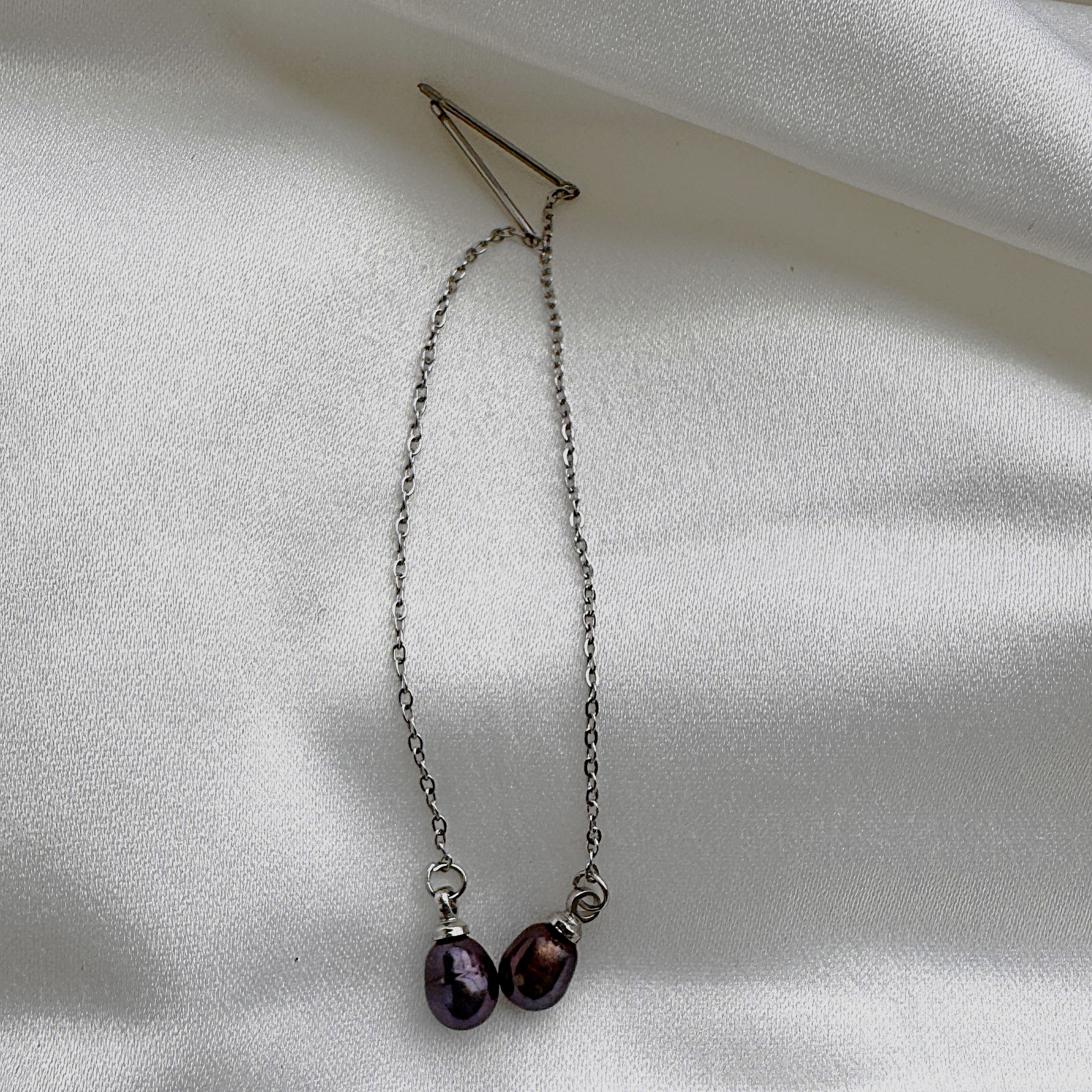 A pair of minimalist Pearl Noire threader earrings with a single deep wine-colored pearl.