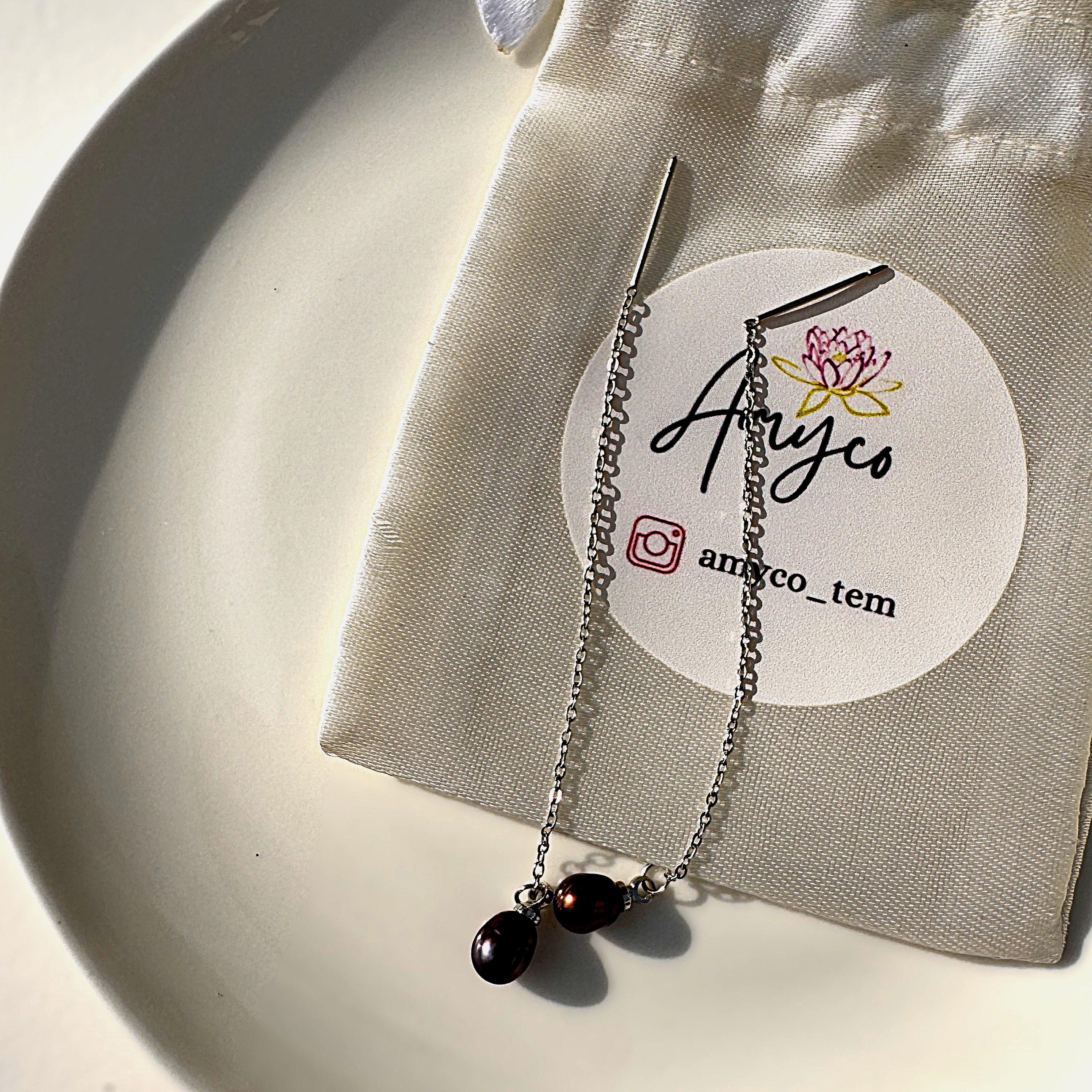 A pair of minimalist Pearl Noire threader earrings with a single deep wine-colored pearl.